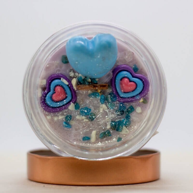 Elberyn candle topped with white howlite, deep blue apatite, and clear quartz crystals, glowing under soft candlelight.